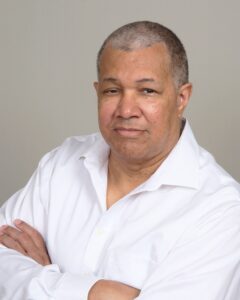 Man in a white shirt with arms crossed.